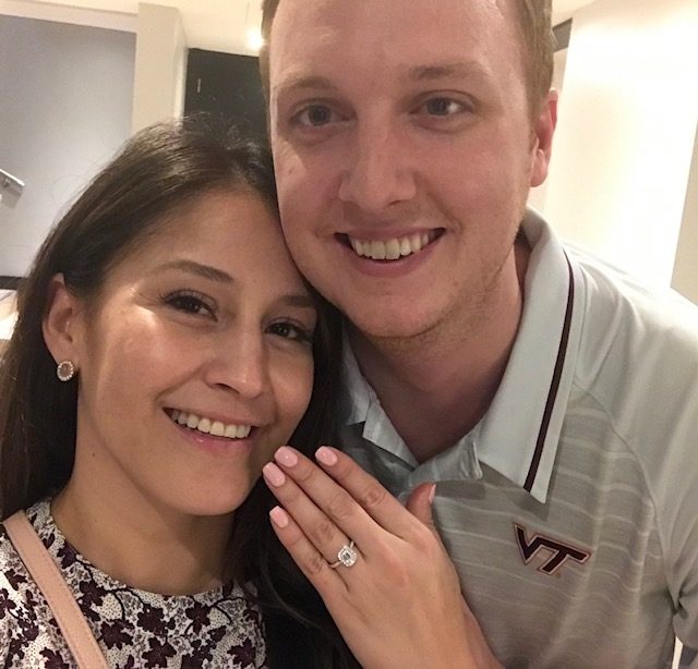 Photo of Erica and Joel after their proposal with Erica showing her engagement ring